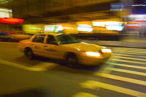 blurred taxi speeds through intersection