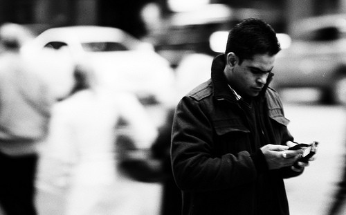 man texting on cell phone in busy street